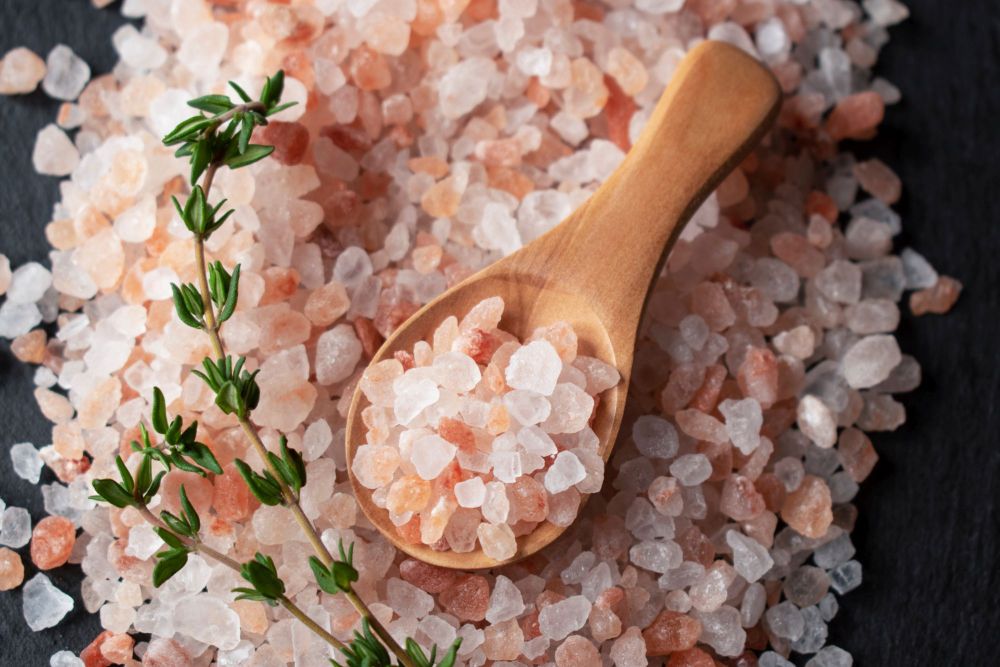 Ein Haufen grobkörniges Himalaya Kristallsalz mit einem Holzlöffel
